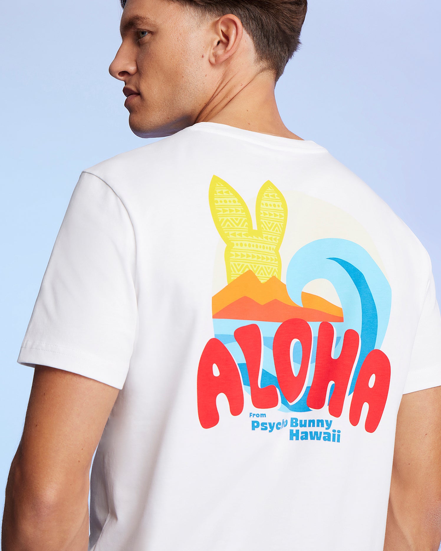 A man is shown from the side wearing a white Pima cotton jersey MENS HAWAII CITY TEE - B6U169Y1PC with a colorful design on the back. The design features the text 
