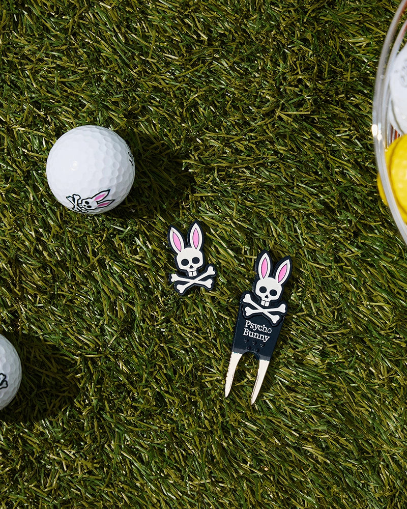 Image shows golf gifts on grass: a golf ball with a bunny skull logo, a black DIVOT TOOL - B6A699C200 featuring the text 