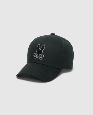 The KIDS ALEXANDER BASEBALL CAP - B0A195E200 by Psycho Bunny is a chic dark green cotton cap featuring an embroidered bunny head above crossed bones on the front. Ideal for kids, this baseball hat stands out against a light gray background, adding a playful yet edgy touch to any outfit.