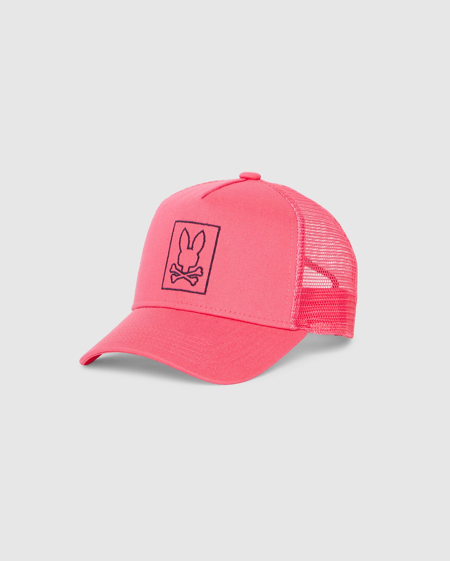 A bright pink Psycho Bunny KIDS LIVINGSTON TRUCKER CAP - B0A401B200 with a mesh back and adjustable snapback strap. The front of the hat features an embroidered bunny design of a bunny head and crossbones in black within a rectangular outline.