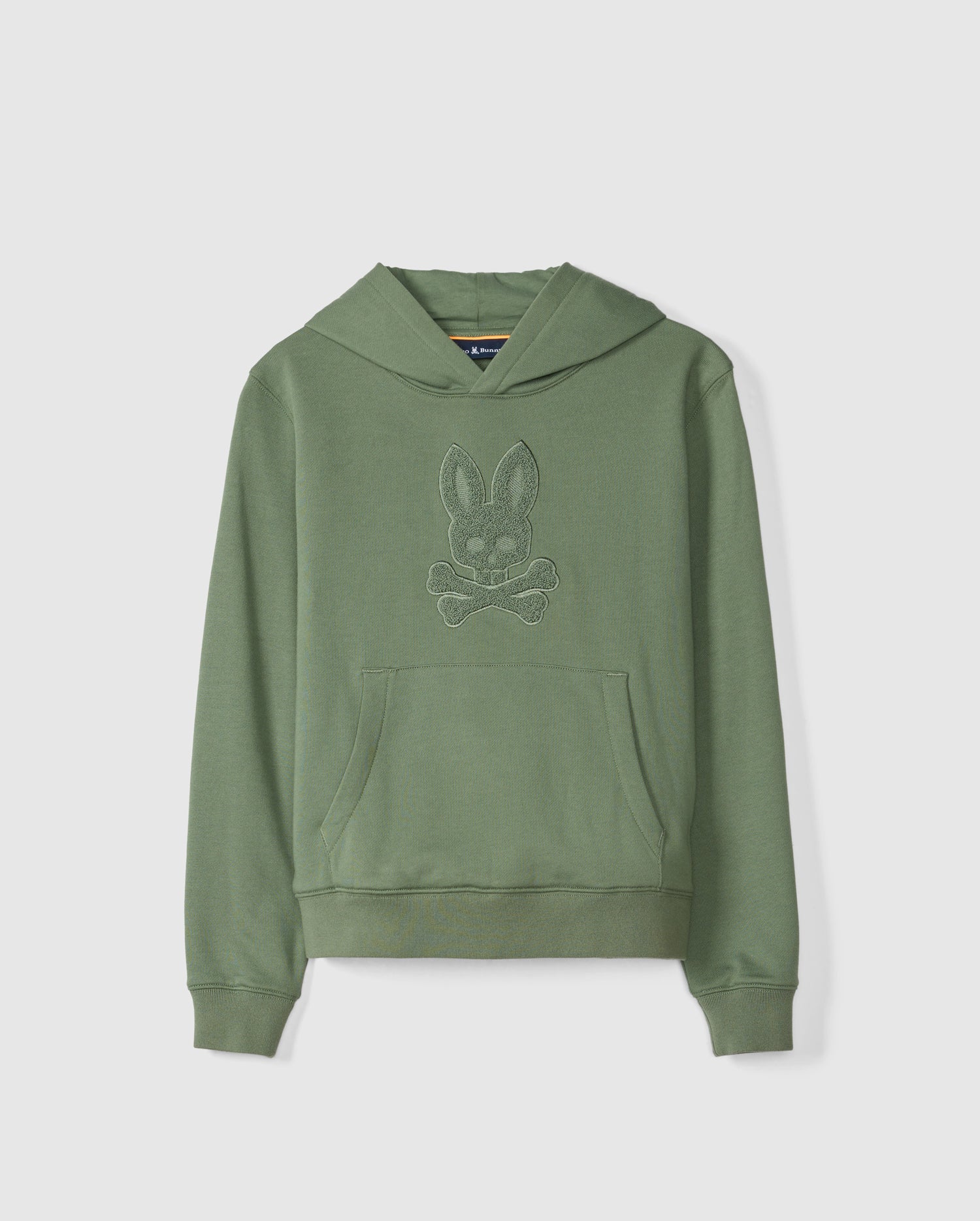 The KIDS PACIFIC CHENILLE HOODIE - B0H930D200 from Psycho Bunny is showcased on a light background. This green French terry hoodie features a chenille-embroidered cartoonish rabbit head with crossed bones, prominently centered on the chest. It's designed with a front pouch pocket and ribbed cuffs and hem for added comfort.