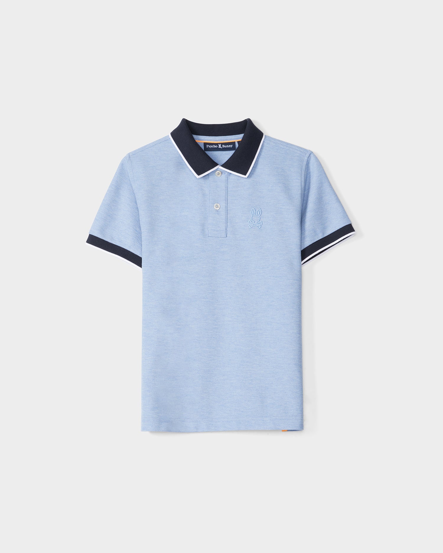 A KIDS WINDCREST PIQUE POLO SHIRT - B0K592C200 in light blue with a color blocked collar and sleeve trim. The dark blue collar features a white stripe on the edge, and the shirt has two buttons at the neckline. A raised-embroidered chest Bunny adorns the left chest area, set against a plain white background by Psycho Bunny.