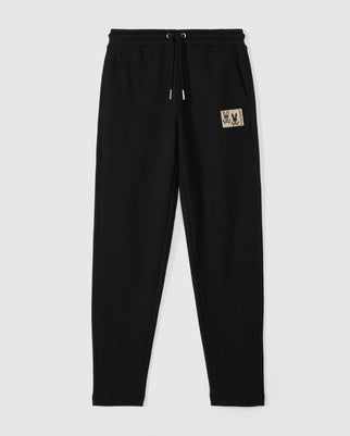 Psycho Bunny's Kids Monroe Twill Patch Fleece Sweatpant (B0P929D200) features a drawstring waistband, two side pockets, and a small tan patch with a stylized design on the upper left. Made from soft cotton fleece for comfort and luxury, they're perfect for casual wear.