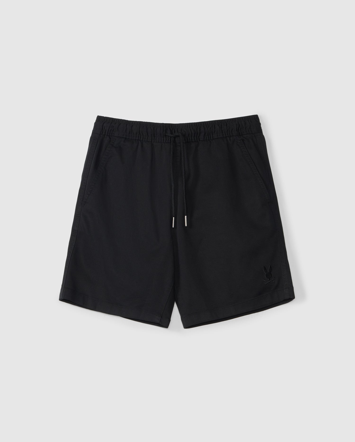 A pair of black athletic shorts with an elastic waistband and a drawstring. The slim fit shorts feature two side pockets and a small embroidered Bunny logo on the bottom left front. Made from a Stretch TENCEL-blend, they are displayed on a plain white background. The product is the KIDS WILLIS STRETCH TENCEL SHORT - B0R239Y1WB by Psycho Bunny.