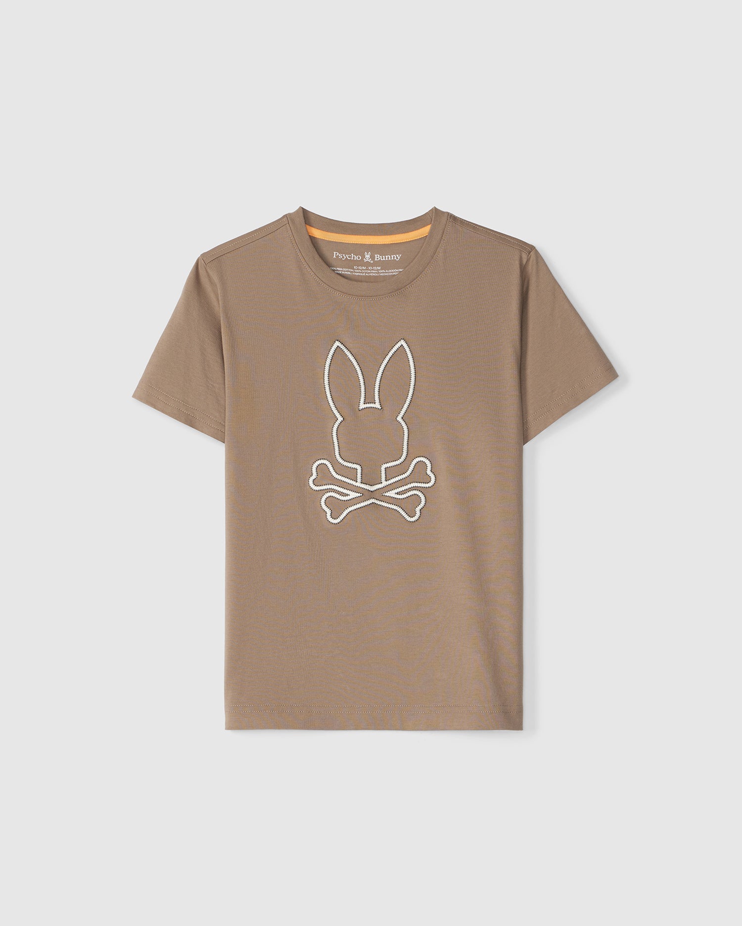 A tan **KIDS FLOYD GRAPHIC TEE - B0U338B2TS** from **Psycho Bunny** features a large white bunny head above crossbones on the front. The T-shirt has a round neckline and short sleeves, with the label reading 