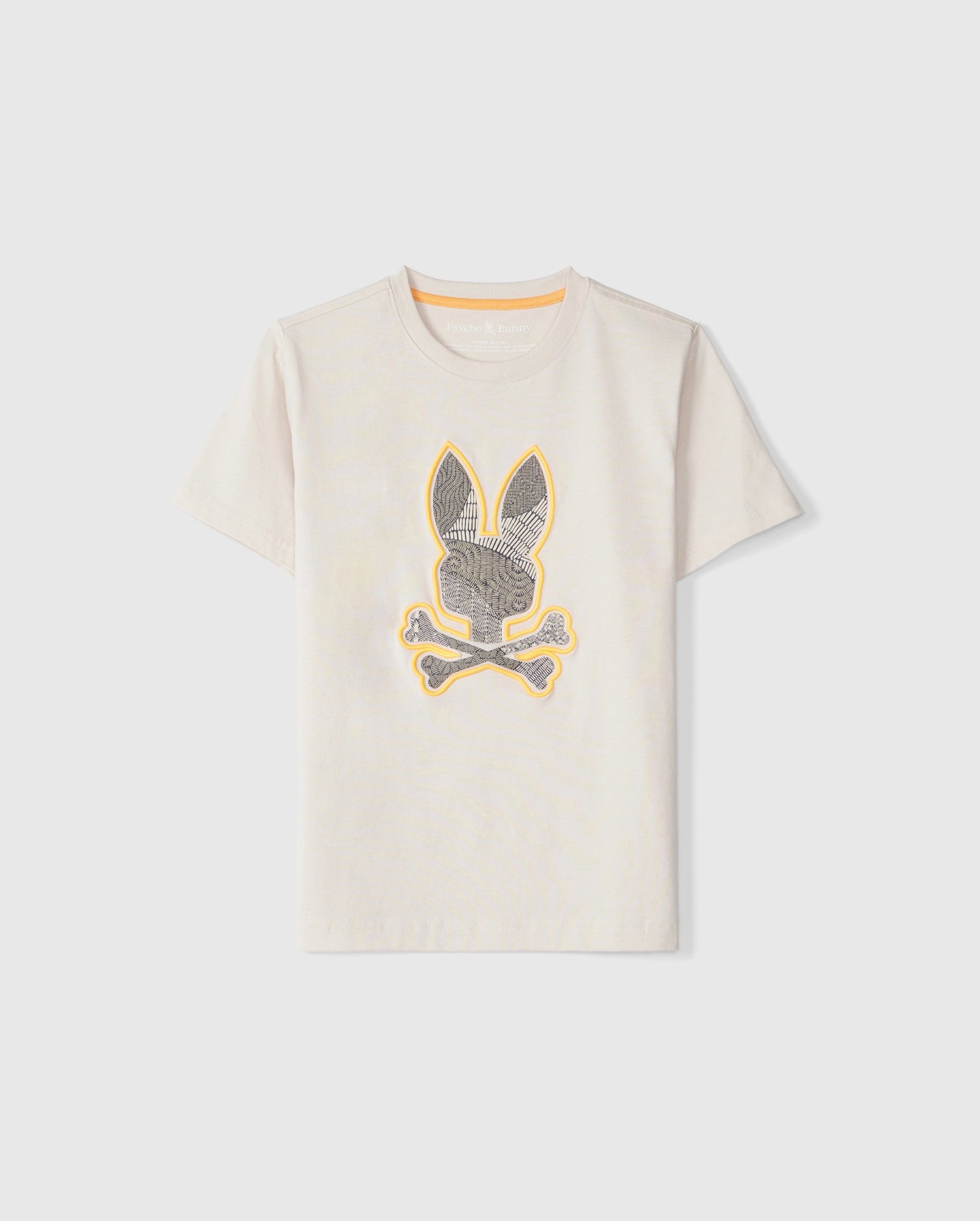 A beige short-sleeved KIDS LENOX EMBROIDERED GRAPHIC TEE - B0U405B200 by Psycho Bunny featuring a design of a bunny head with crossbones below it in the center. The intricate embroidery is in black with a yellow outline, perfect for adding a touch of spring style. The shirt is displayed against a white background.