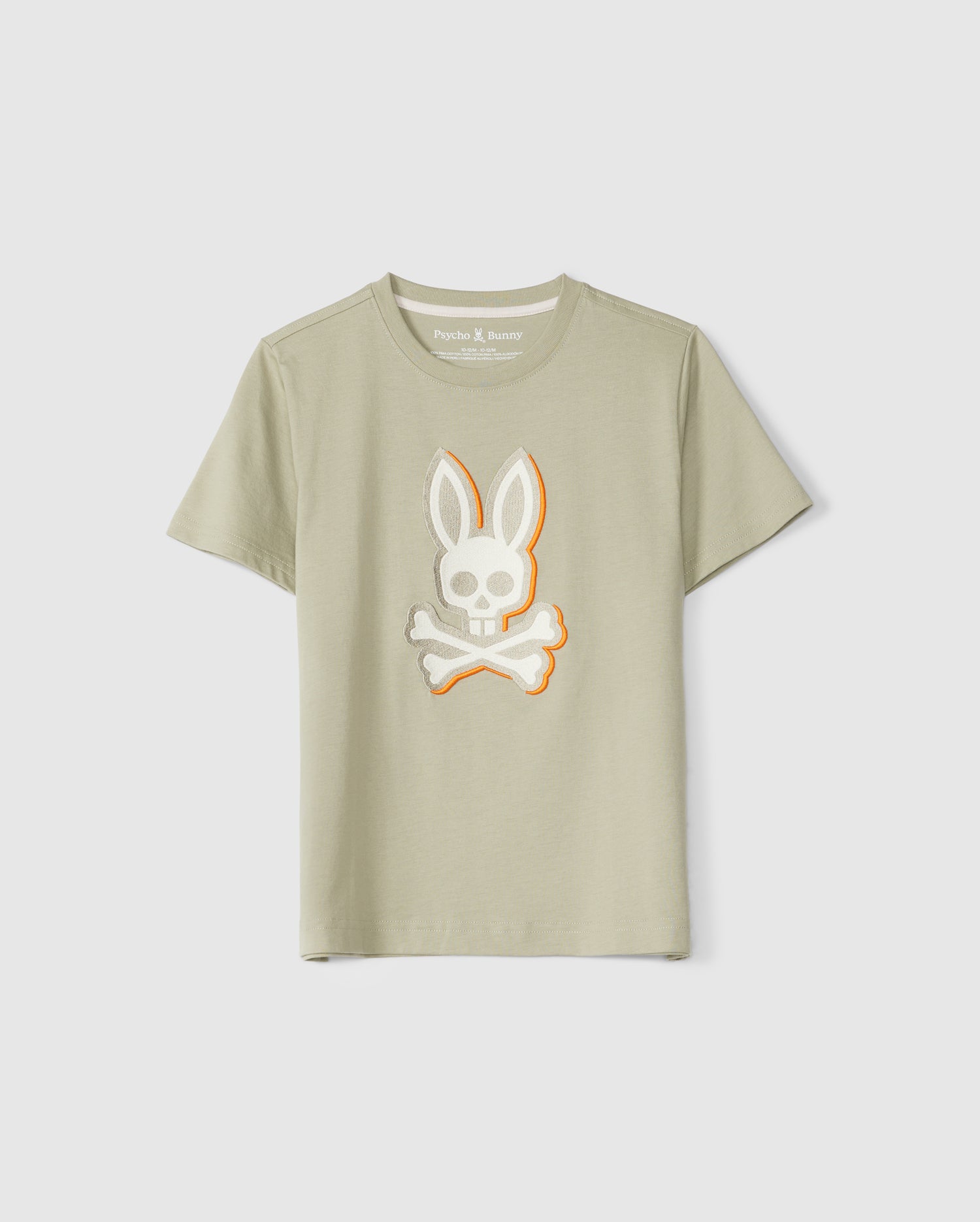 A light olive-green KIDS KAYDEN GRAPHIC TEE - B0U676C200 from Psycho Bunny featuring a Bunny embroidered logo with a skull and crossbones design in the center. The bunny has long ears, and the crossbones are positioned below the skull. The background is a neutral light gray.