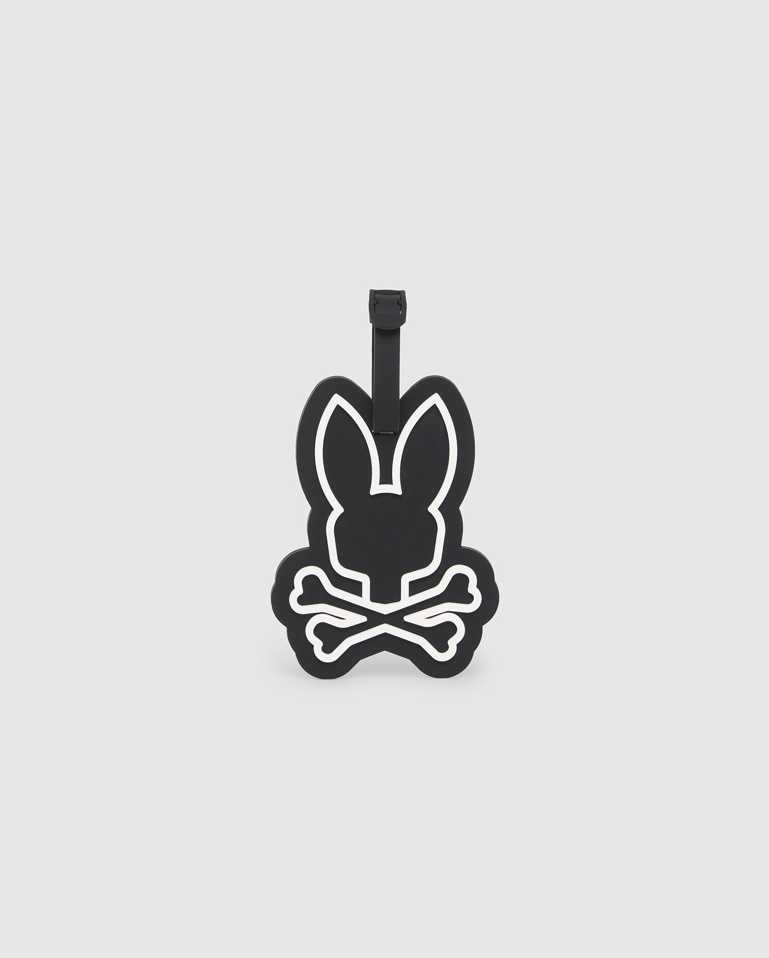 A black, minimalistic Psycho Bunny MENS LUGGAGE TAG - B6A392B200 features an outline of a bunny's head with long ears and crossed bones beneath it. White lines define the shapes, and a black strap at the top allows for easy attachment. The tag includes a silicone body and a transparent slot for your information card.