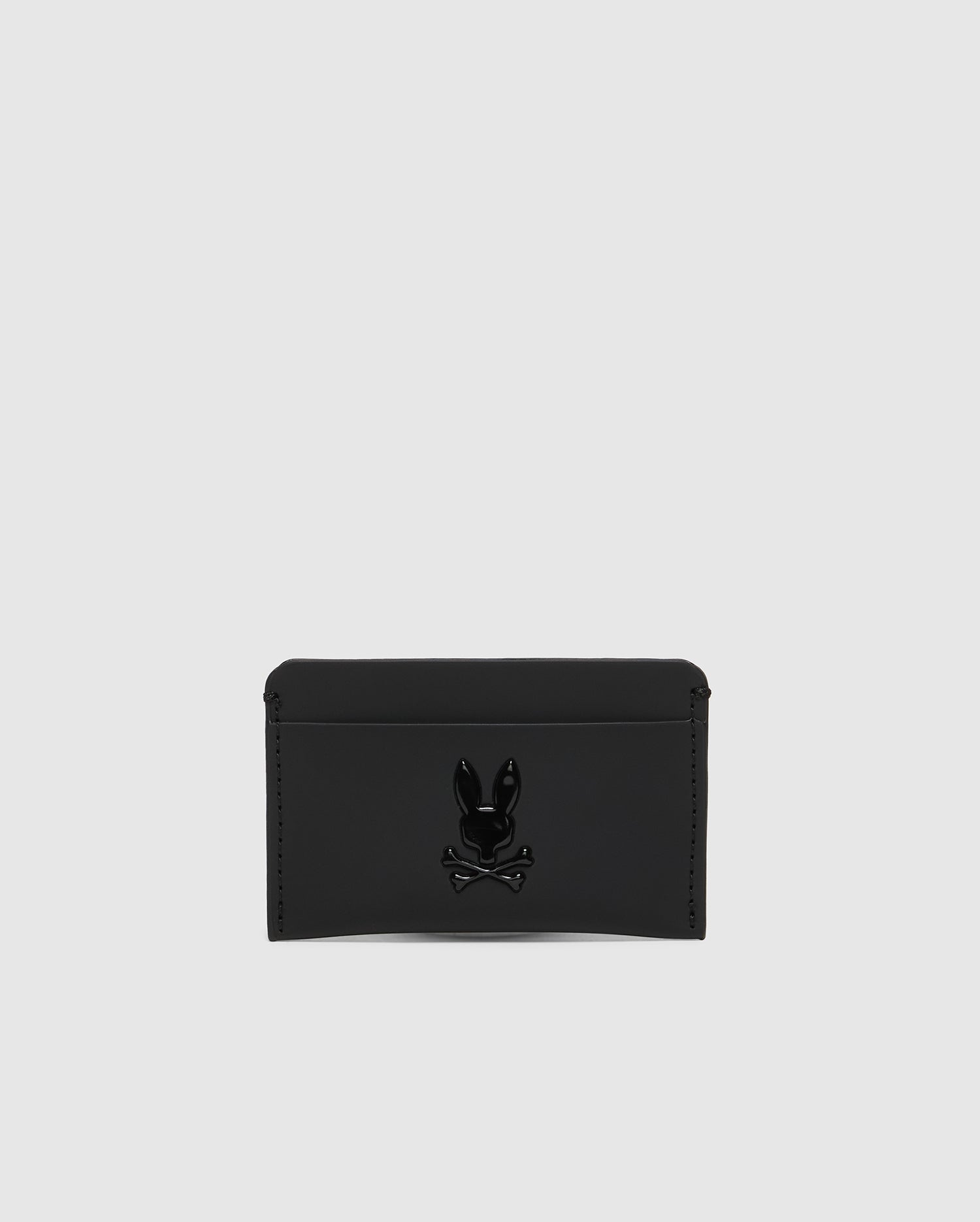 The Psycho Bunny MENS RUBBERIZED CARD CASE - B6A473F200 is a black leather wallet with a minimalist design, featuring an embossed skull and crossbones logo with rabbit ears, centered on the front. Its sleek light gray color ensures peace of mind while keeping your belongings safe.