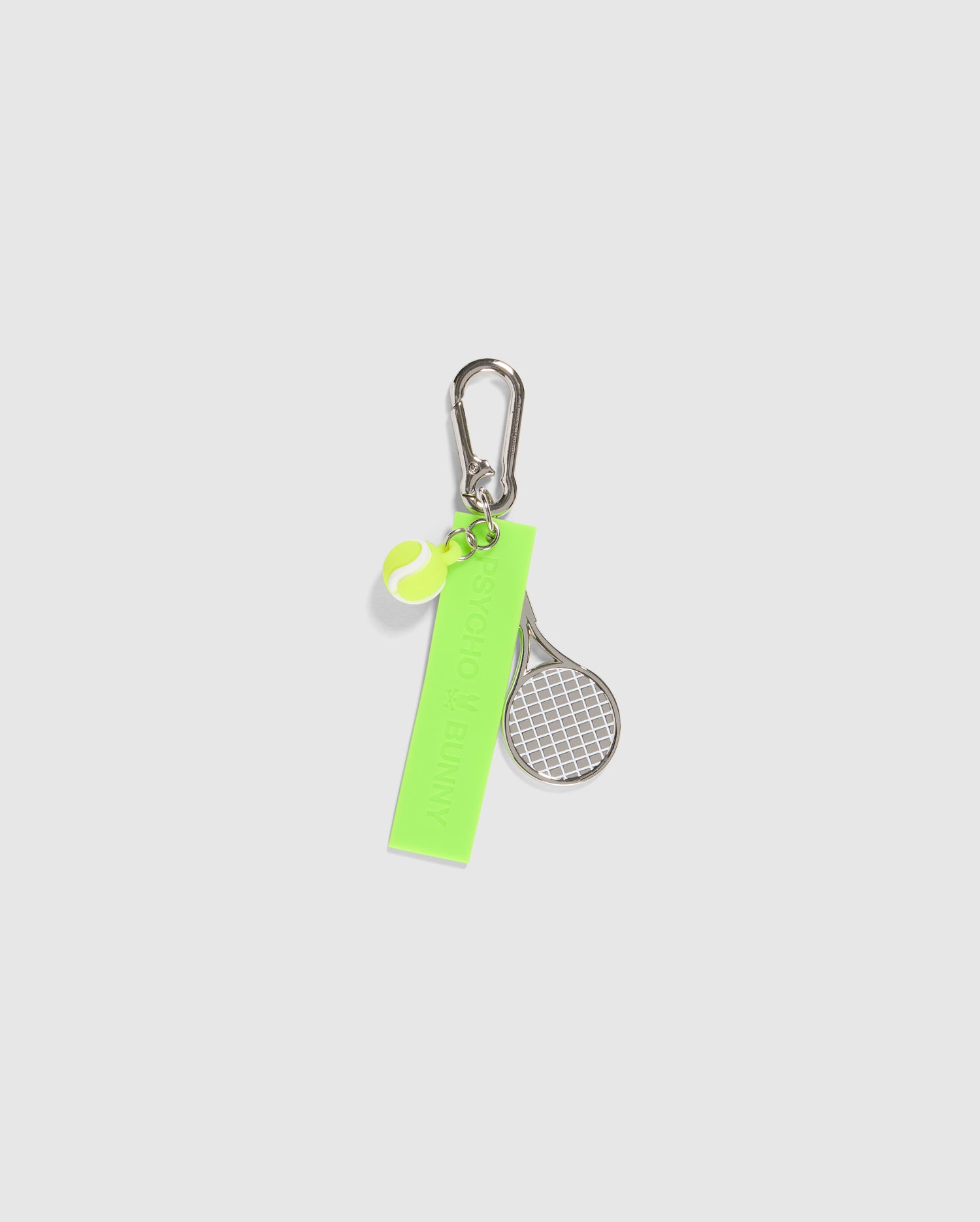 A Psycho Bunny TENNIS LONG KEYCHAIN - B6A705C200 featuring a bright green rectangular tag, a small tennis racket charm, and a neon green tennis ball charm. The tag has text on it, and the carabiner keychain is attached to a silver clip. All items are on a plain white background.