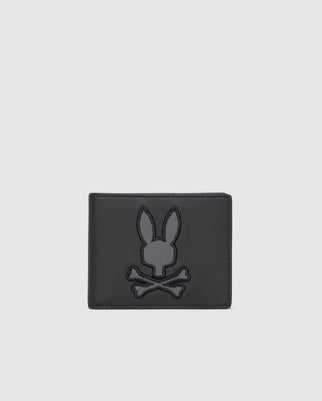 Introducing the Psycho Bunny Men's Leather Wallet - B6A868D200, a luxurious accessory crafted in black leather. It features an embroidered design of a bunny skull above crossed bones on the front, set against a plain light gray background, making it an exceptional choice for those looking for a premium leather wallet.