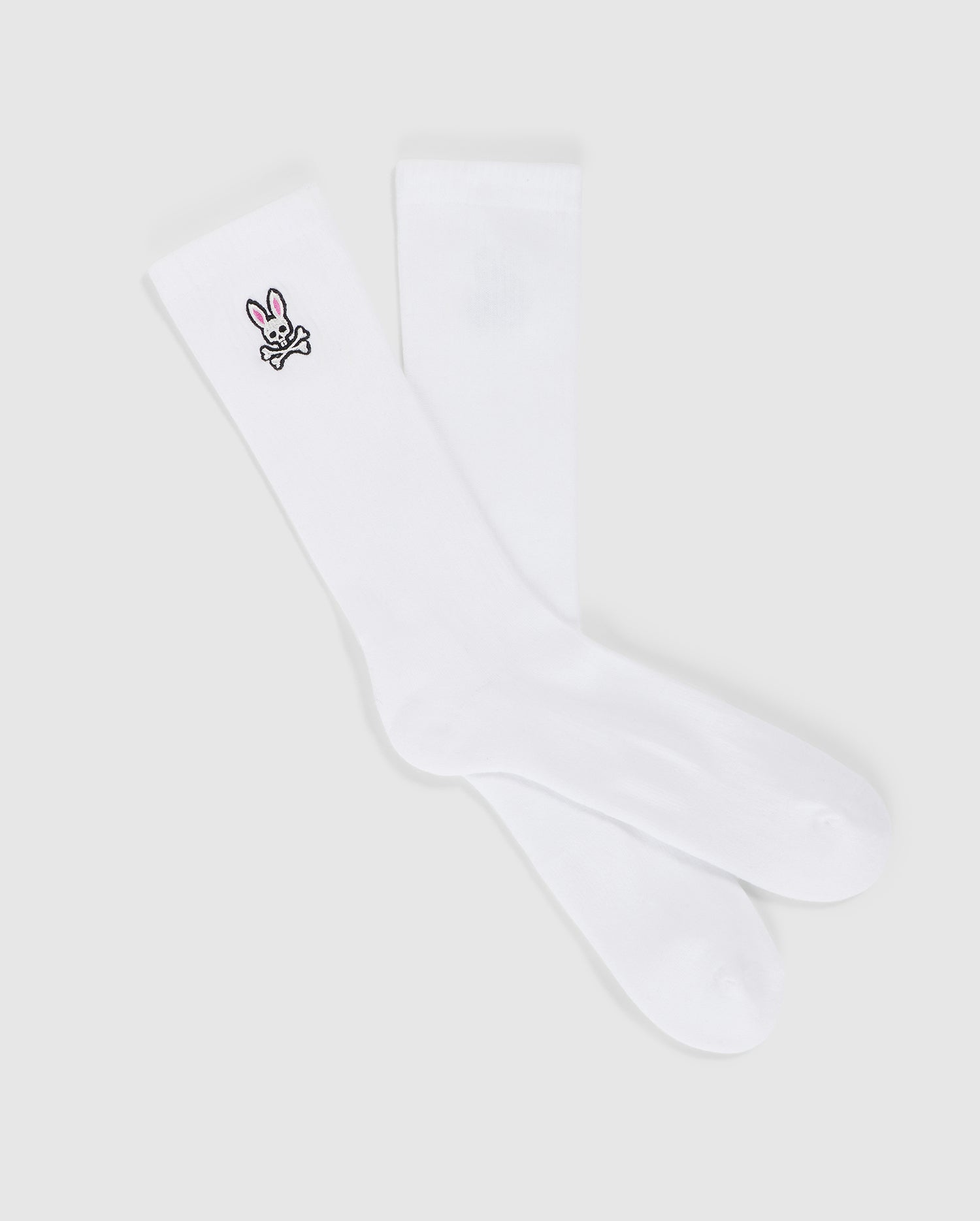 A pair of MENS FASHION SOCKS - B6F486C200 from Psycho Bunny, made from luxurious Pima cotton, featuring a small embroidered bunny design near the top. The bunny is depicted in black outline with a pink nose and ears, adorning only one sock. These stylish socks are made in Peru and offer both comfort and charm.