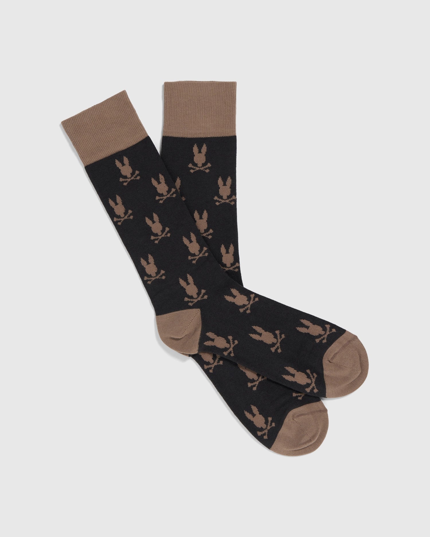 A pair of black MENS DRESS SOCK - B6F750B2SO by Psycho Bunny, made in Peru, with brown cuffs, heels, and toes. The Peruvian Pima cotton socks feature a repeating pattern of brown eagle silhouettes.
