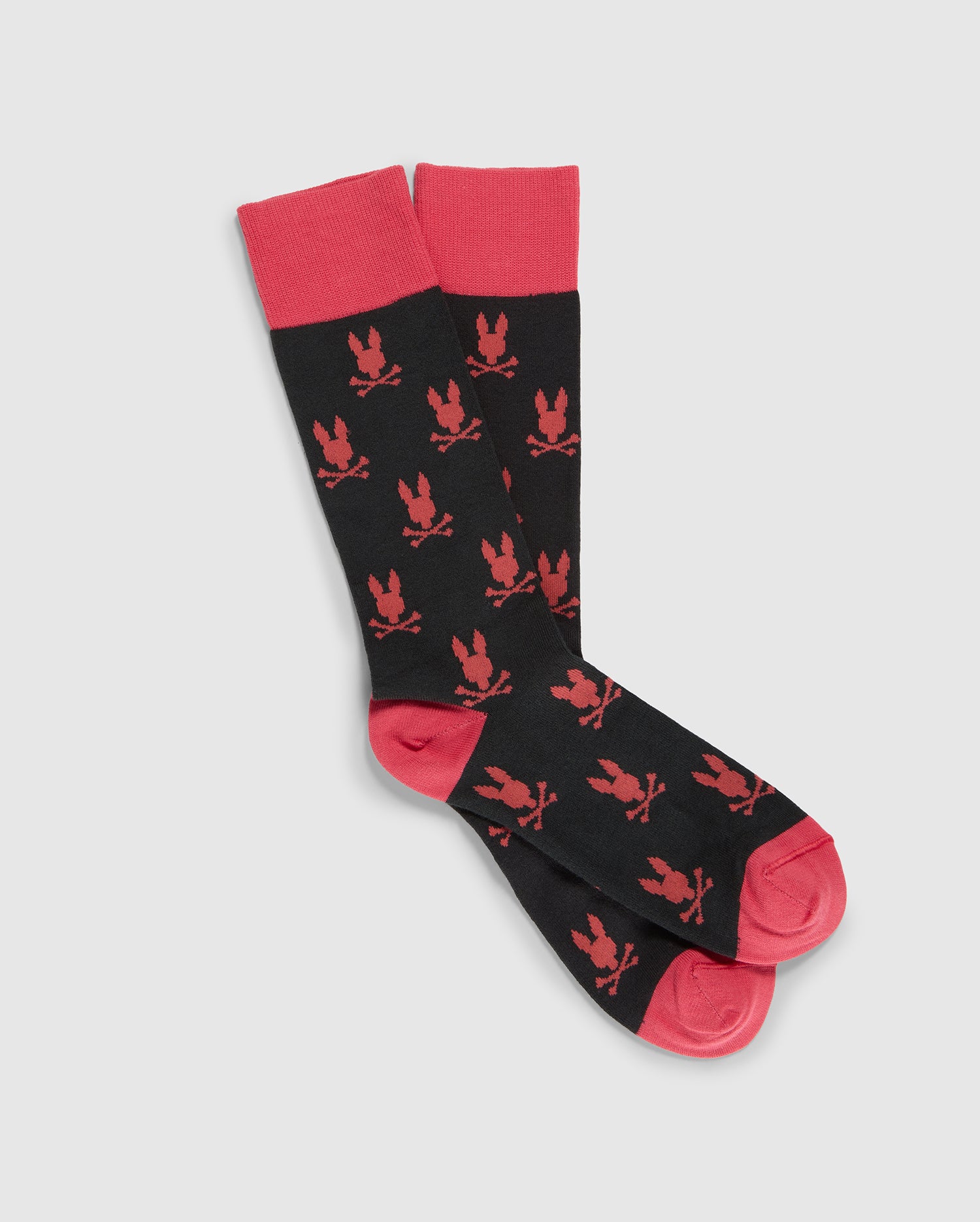 A pair of black and red MENS DRESS SOCK - B6F750B2SO by Psycho Bunny with a repeating pattern of red illustrations featuring a crown and a bird. Made from luxurious Peruvian Pima cotton, the socks have red cuffs, toes, and heels. The design is eye-catching and bold.