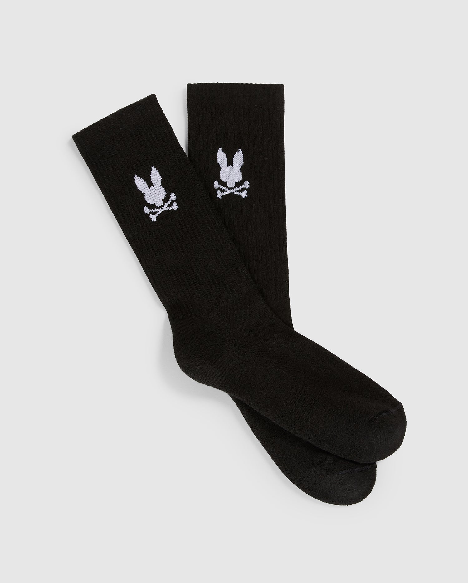 A pair of black Psycho Bunny MENS SPORT SOCK - B6F775C200 featuring a white design of a rabbit skull and crossbones toward the top. Made from luxurious Peruvian Pima cotton with a hint of stretch, these socks are laid out on a plain white background, with one sock slightly overlapping the other.