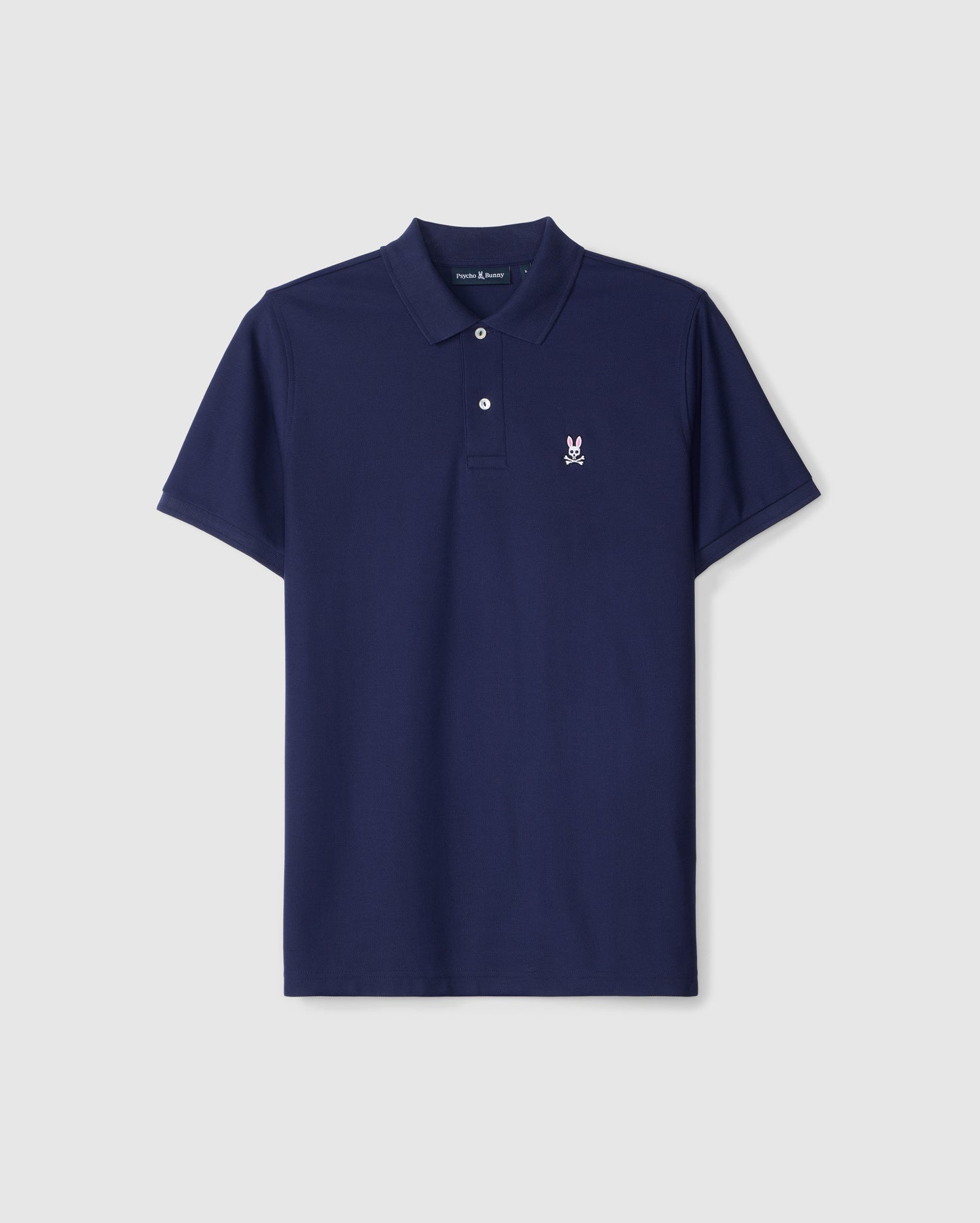 The Psycho Bunny MENS CLASSIC PIQUE POLO SHIRT - B6K001CRPC in navy blue is crafted from luxurious Peruvian Pima cotton. This short-sleeved polo features a collar, three buttons, and a small white embroidered emblem of a rabbit on the left chest. The shirt is showcased against a plain white background.