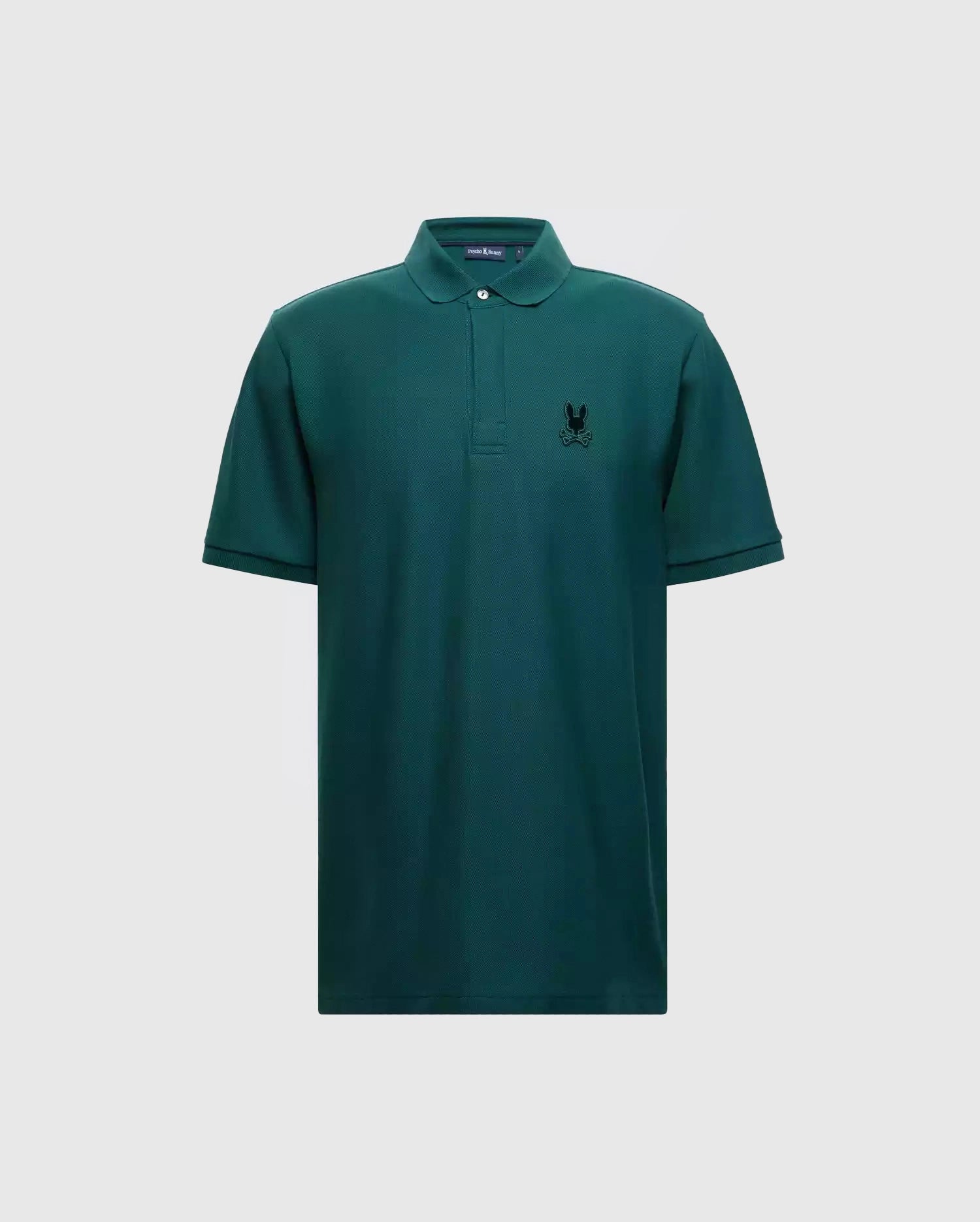 Introducing the MENS BRANSON PIQUE POLO - B6K108E200 by Psycho Bunny: a classic men's polo crafted from premium materials, featuring a stylish green color with short sleeves and a collar. It boasts a small black Psycho Bunny logo on the left chest for subtle branding, all elegantly showcased against a plain grey background.