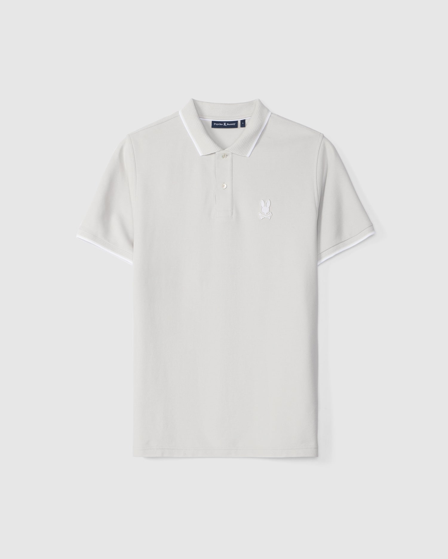 White Psycho Bunny polo shirt displayed against a plain background, featuring a small embroidered logo on the left chest, short sleeves, and a button-up collar with mother-of-pearl buttons.