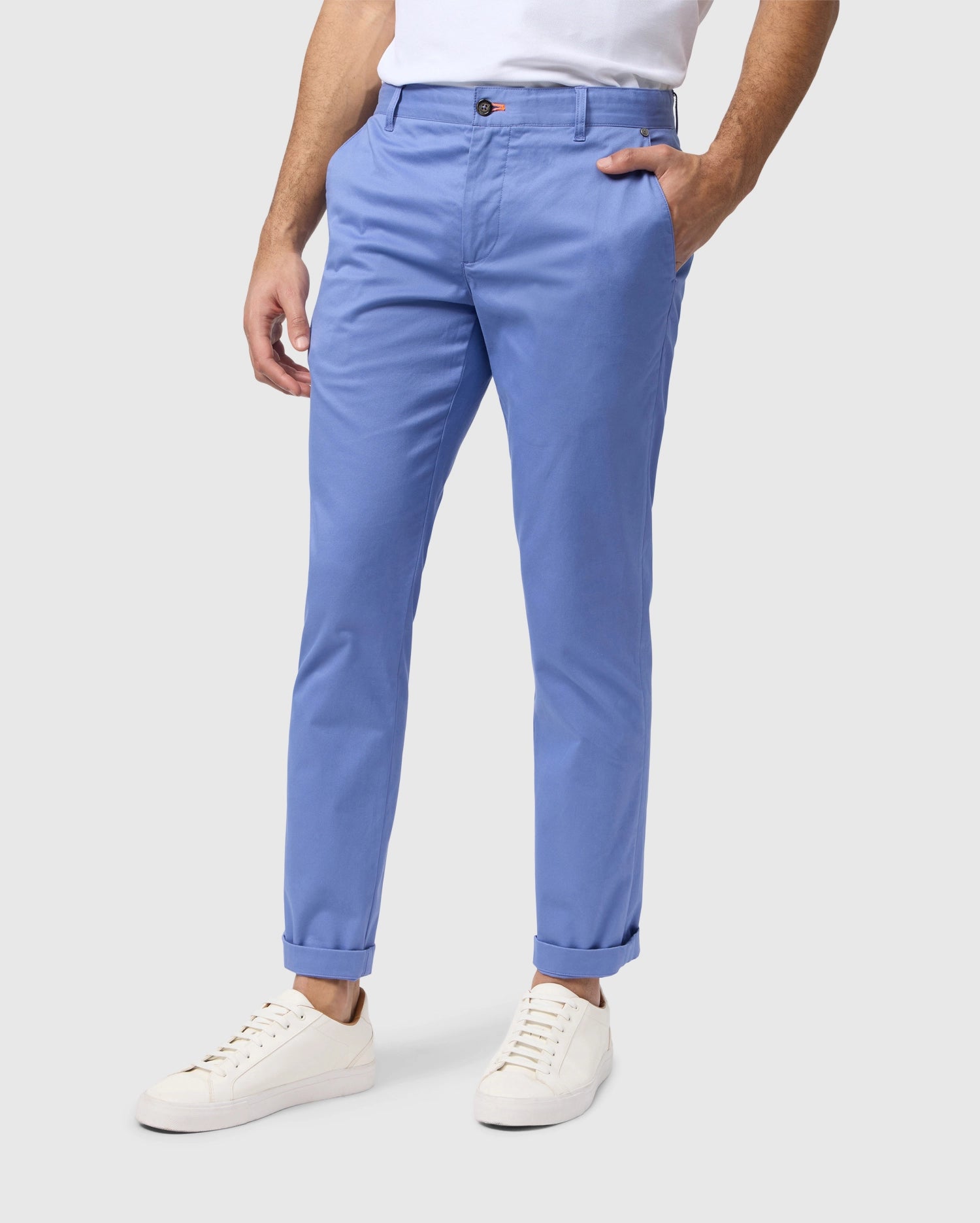 A man wearing light blue embroidered Psycho Bunny chino pants and white sneakers, cropped to show from the waist down against a neutral background.