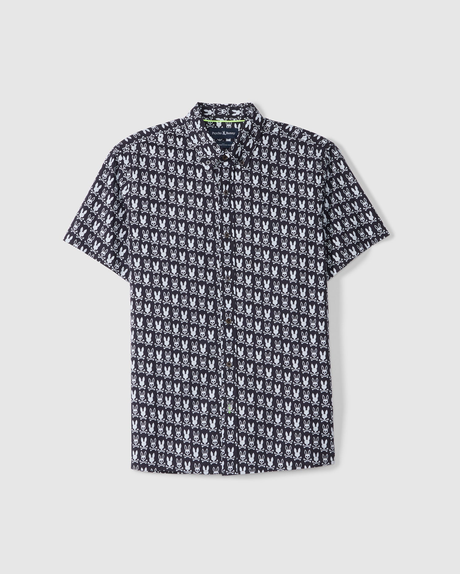 The MENS TILDEN ALL OVER PRINT BUNNY SHIRT - B6Q898D200 by Psycho Bunny is displayed against a plain white background. This black short-sleeve button-up shirt features a repetitive white bunny pattern and contrasting piping, along with a pointed collar and a front pocket.