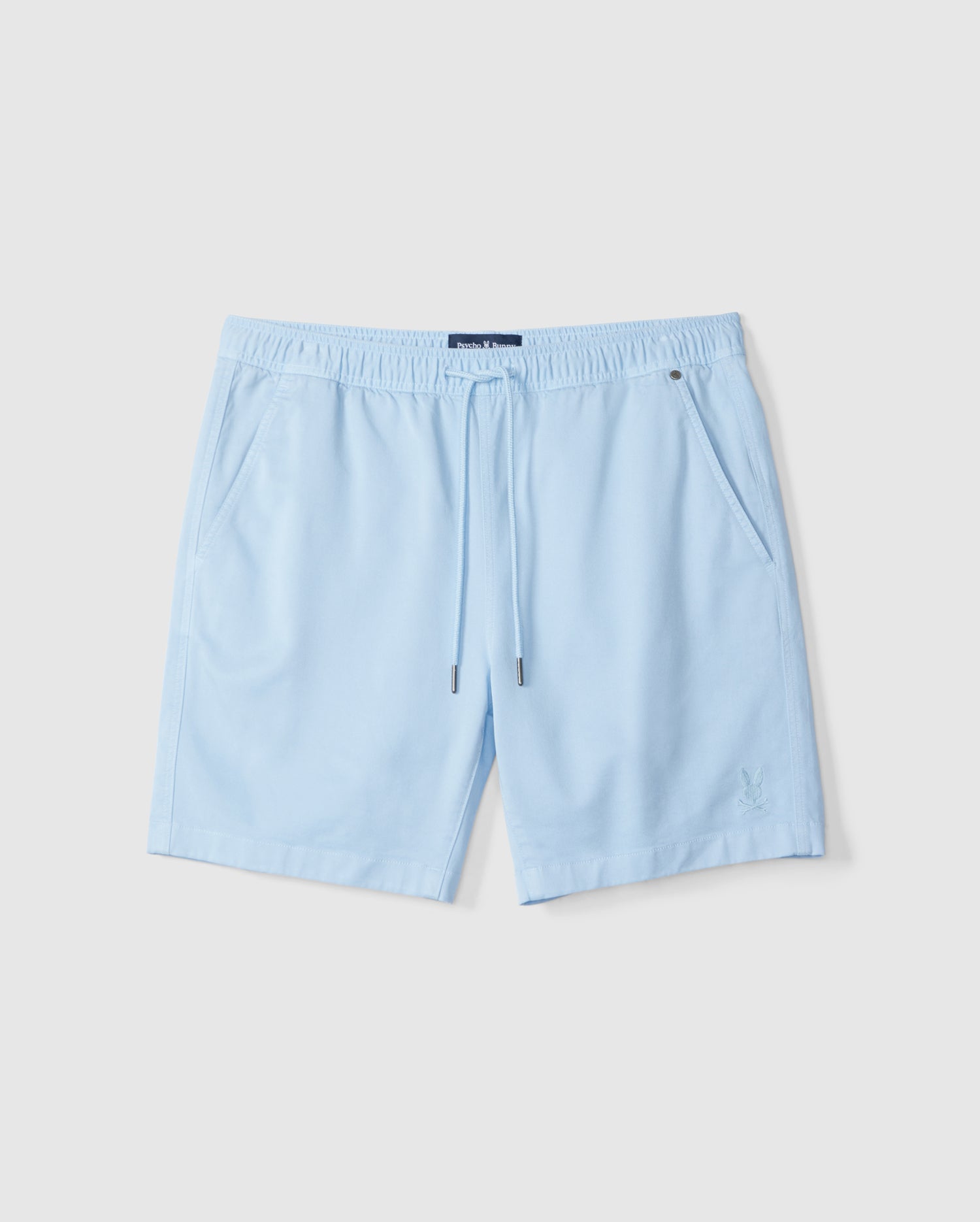 Light blue swim shorts with an elastic waistband and drawstring, displayed on a plain white background. The left leg features a small, dark embroidered logo of the MENS WILLIS STRETCH TENCEL SHORT from Psycho Bunny.