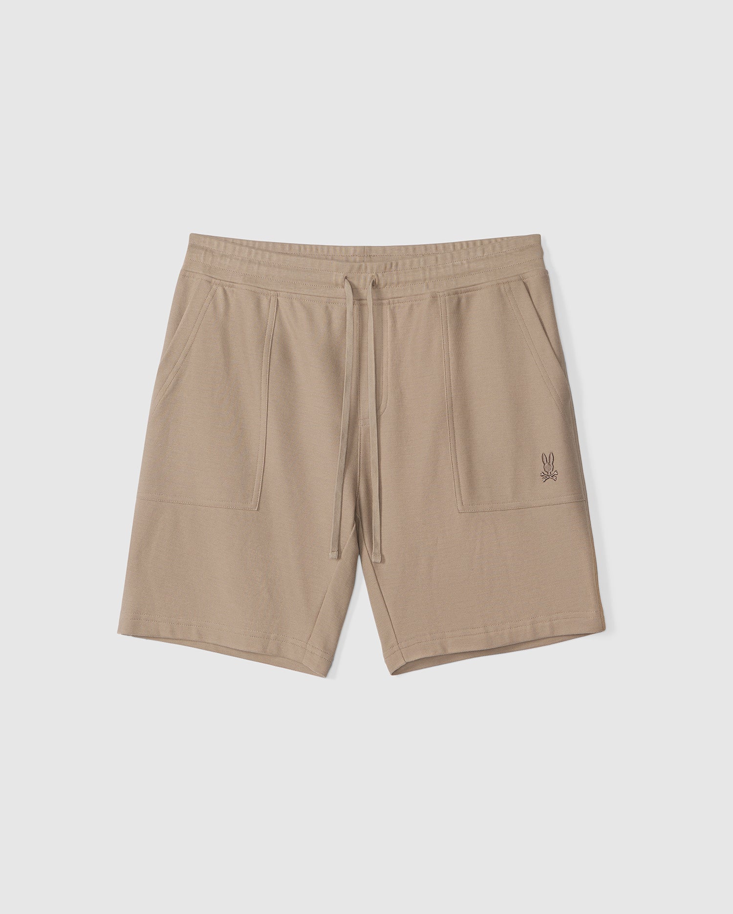 A pair of beige MENS STANFORD LIGHT PIQUE SWEATSHORT - B6R344B200 by Psycho Bunny with an elastic waistband and drawstring. The shorts, crafted from soft Pima cotton, boast two front pockets and a small embroidered bunny design on the left pocket. This comfortable apparel is a stylish wardrobe staple. The background is plain white.