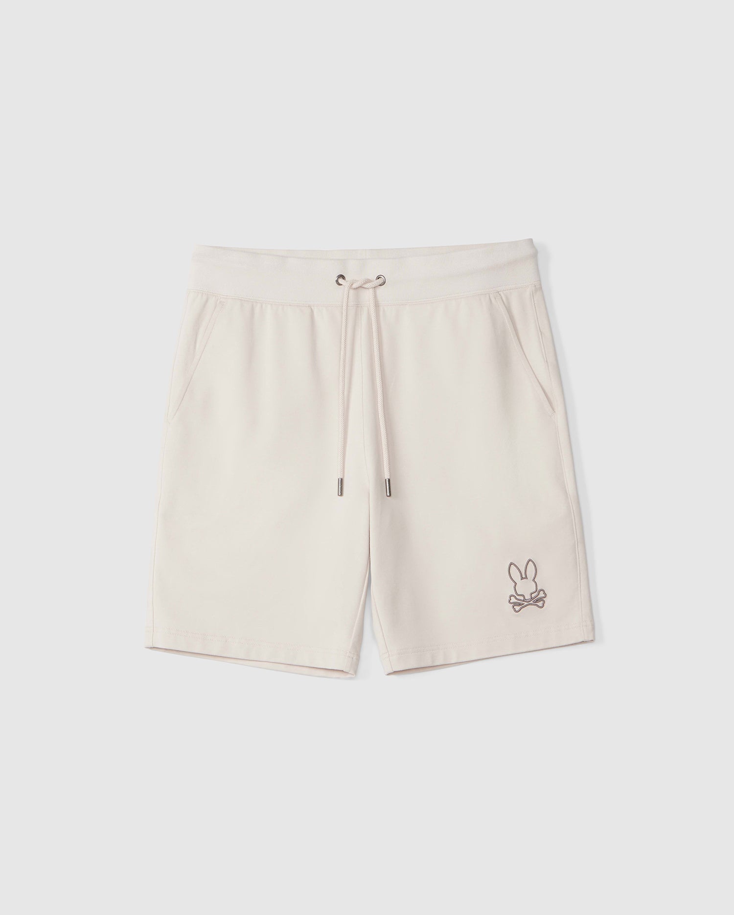 Cream-colored Psycho Bunny MENS LIVINGSTON SWEATSHORT - B6R408B200 with a small embroidered rabbit design on the left leg and zippered pockets, displayed against a white background.