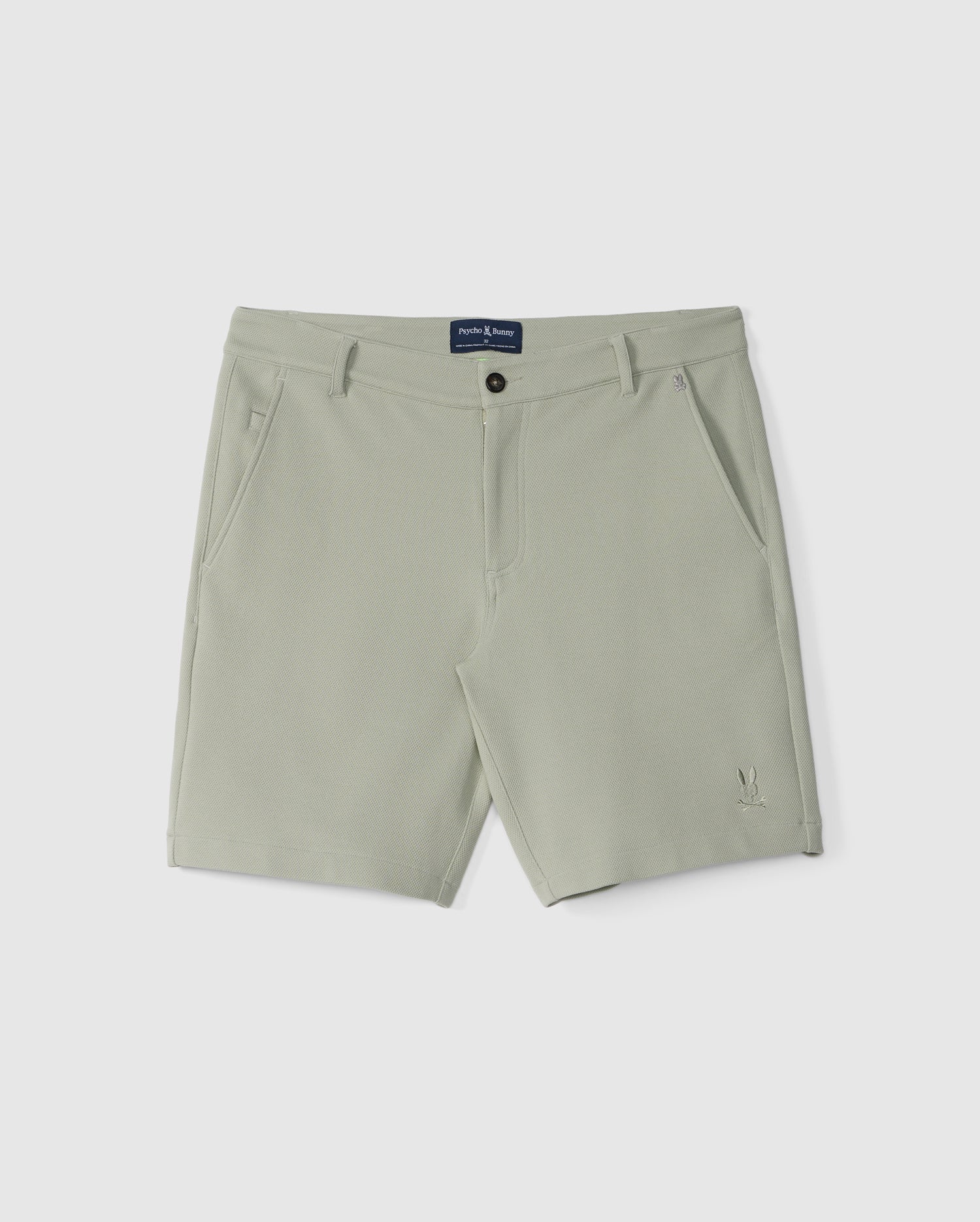 Light green, flat-front Men's Shiro Knit Honeycomb Shorts with belt loops and a button closure, displayed on a white background. Made from sweat-wicking honeycomb fabric, the shorts feature side pockets and a small Psycho Bunny logo embroidery near the hem.