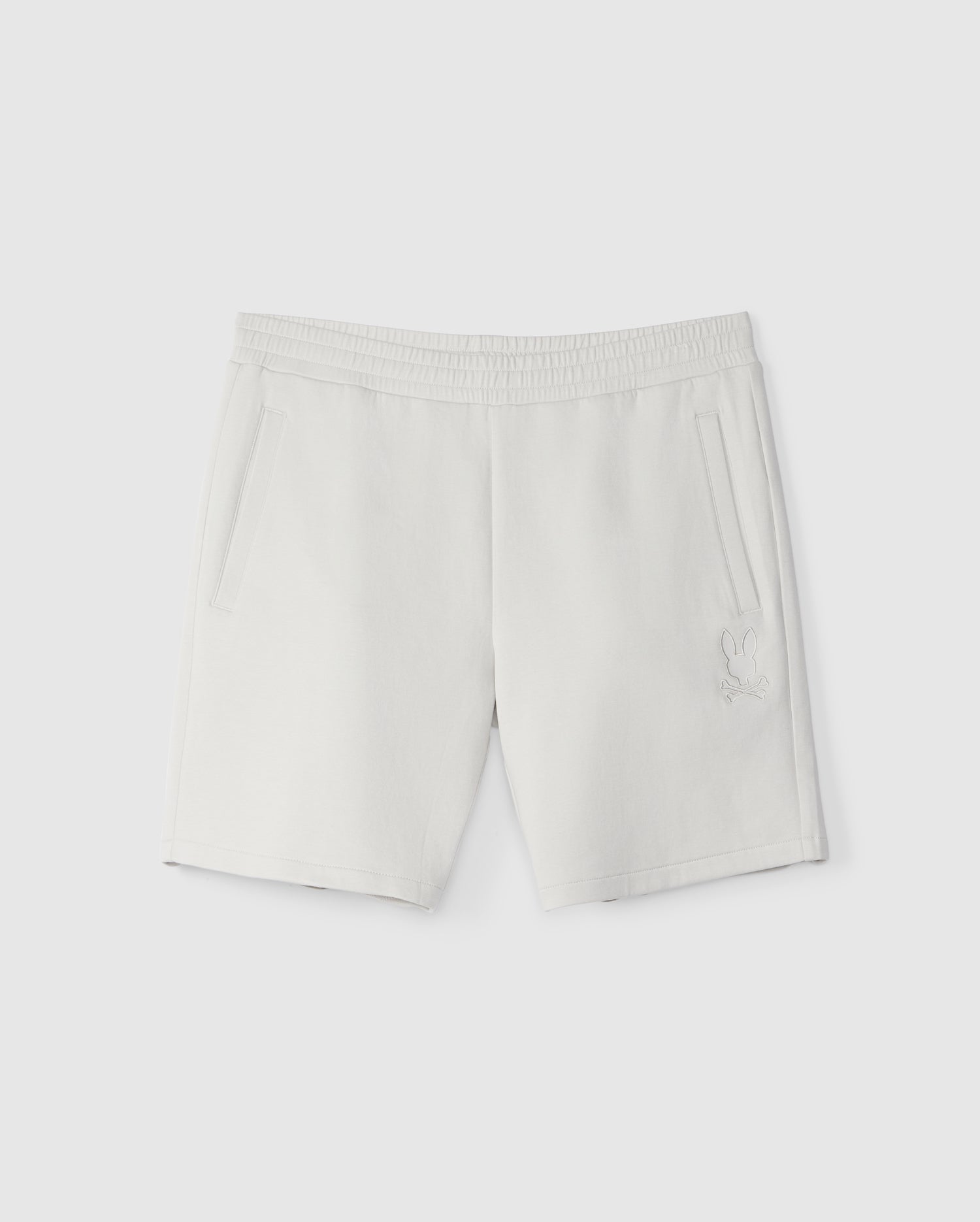White Psycho Bunny sweatshorts with an elastic waistband and side pockets, featuring a small embroidered logo on the lower left leg, displayed against a plain background.