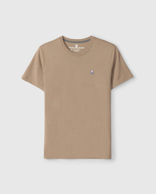 Psycho Bunny's Men's Classic Crew Neck Tee in beige, made from 100% Pima cotton, highlights the iconic embroidered Classic Psycho Bunny logo on the left chest and is featured against a light gray background.