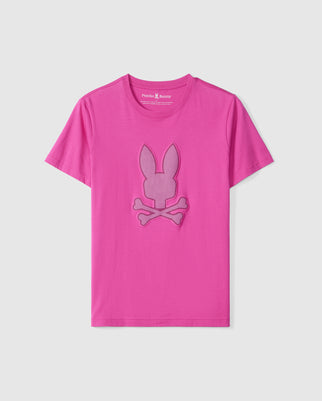 The MENS RIVIERA GRAPHIC TEE - B6U639C200 from Psycho Bunny features a vibrant pink color made from luxurious Peruvian Pima cotton. It showcases a large, stylized bunny head and crossbones design on the front in a slightly darker shade of pink, with the "Psycho Bunny" label visible at the neckline. The T-shirt is displayed on a plain white background.