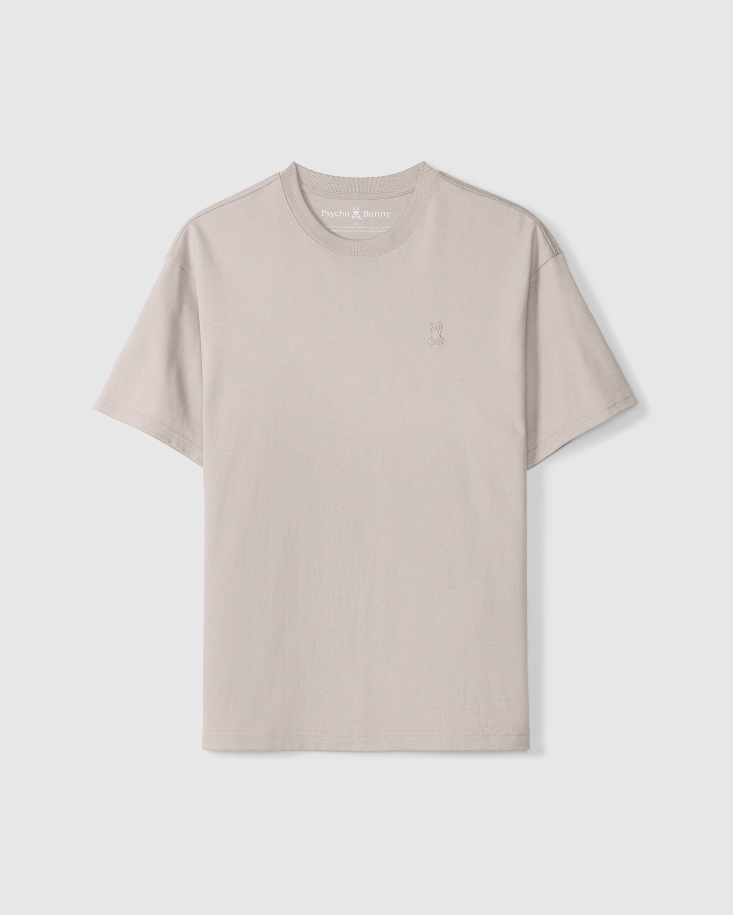 The MENS DUKE OVERSIZED TEE - B6U742D200 from Psycho Bunny is a plain, light beige t-shirt made from heavyweight Pima cotton. It features a subtle small embroidered chest bunny on the left. This relaxed fit tee includes a classic crew neck and short sleeves, set against a white background.