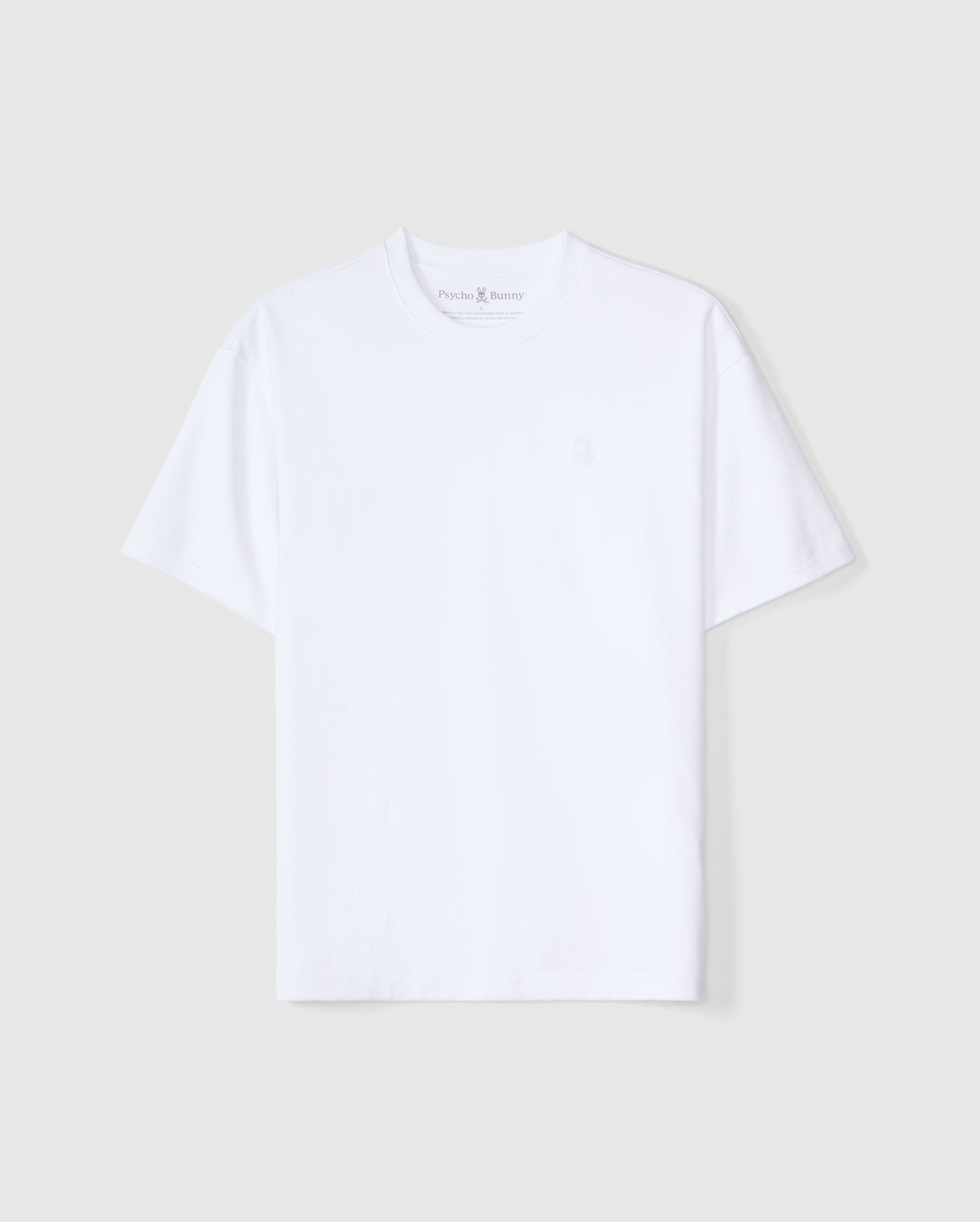 The MENS DUKE OVERSIZED TEE - B6U742D200 from Psycho Bunny is a heavyweight Pima cotton short-sleeve T-shirt in a solid plain white color, featuring a round neck. It showcases a subtly embroidered small logo on the left chest area and provides a relaxed fit against an off-white background.