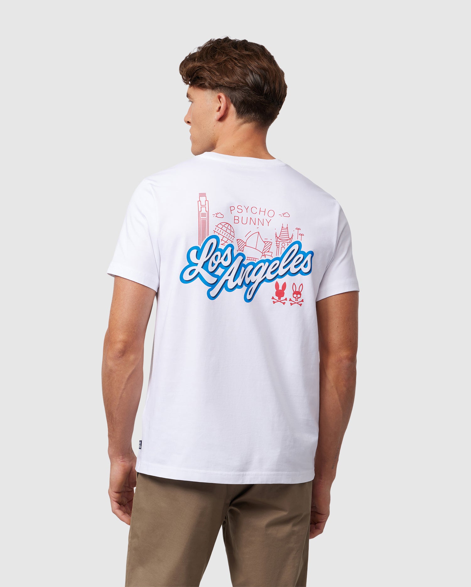 A man is wearing a MENS LOS ANGELES CITY TEE - B6U861A2PC, crafted from soft Pima cotton. The white T-shirt features a colorful design on the back, with 