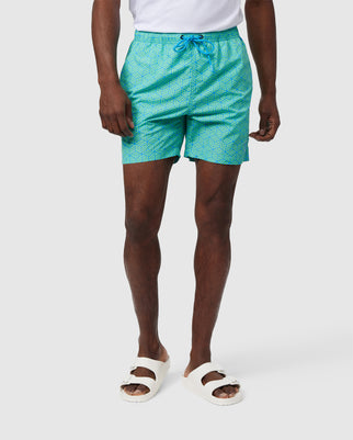 Man wearing Psycho Bunny Mens Jasper Lightweight Swim Trunk - B6W168B2SW and white sandals, standing against a plain background, showing only from the waist down.