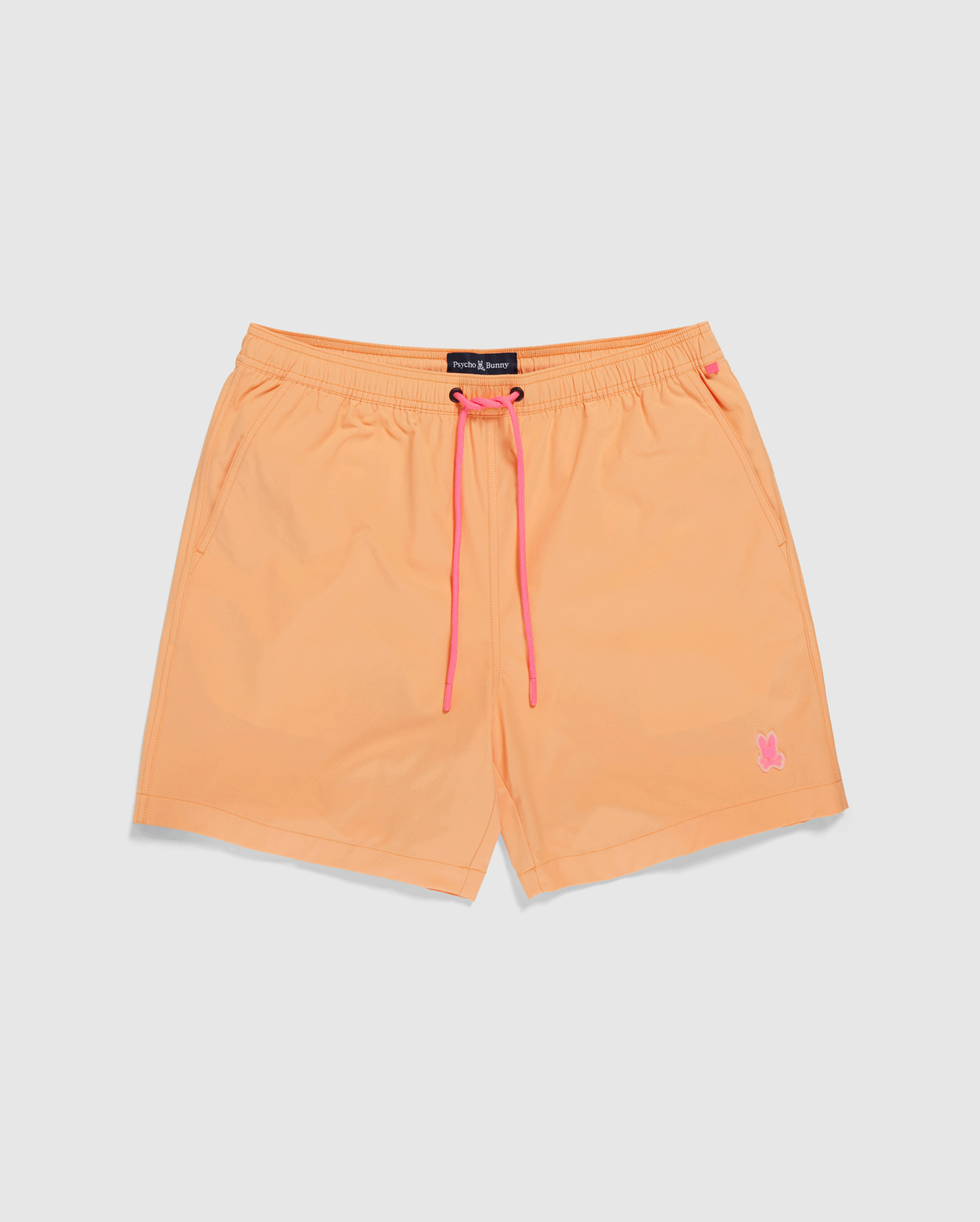 Bright orange Psycho Bunny swim trunks with a pink drawstring and a small pink logo on the lower left leg, displayed against a plain white background.