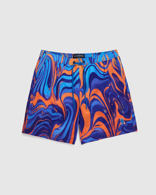 A pair of Psycho Bunny MENS NEVADA ALL OVER PRINT SWIM TRUNK - B6W526C200 featuring a vibrant swirl print of psychedelic blue, purple, and orange colors. The quick-dry fabric shorts have an elastic waistband and are displayed against a plain white background.