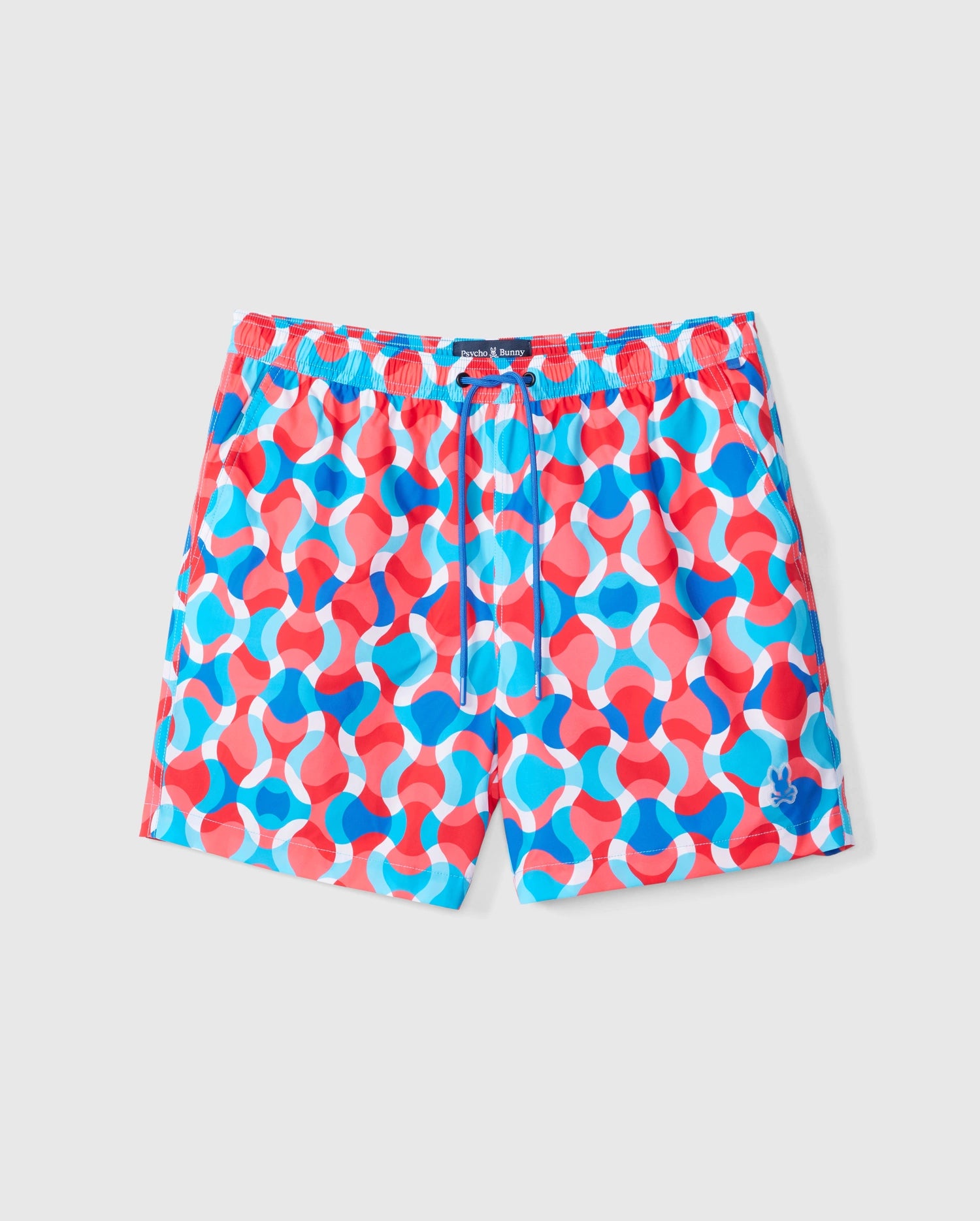 The Psycho Bunny MENS WALTER LIGHTWEIGHT PRINT SWIM TRUNK - B6W863D200 boasts a vibrant, geometric pattern of interlocking shapes in red, blue, and white hues. Made from 100% polyester, these colorful shorts feature an elastic waistband with a drawstring and a small embroidered logo on the bottom left leg. The background is plain light gray.